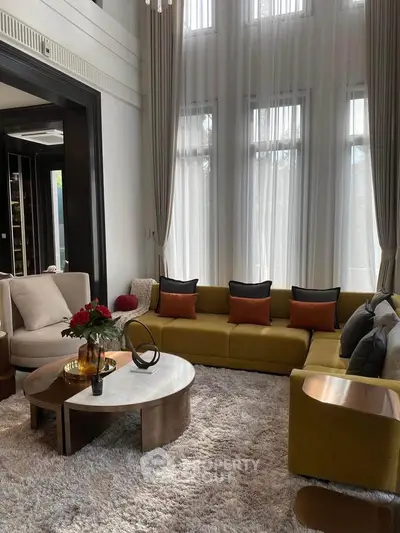 Luxurious living room with high ceilings, elegant decor, and large windows for natural light.