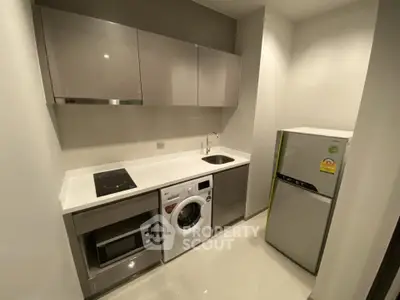 Modern compact kitchen with sleek cabinets, washing machine, and fridge in a stylish apartment.