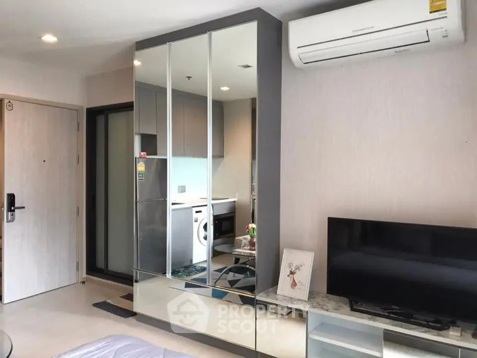 Modern apartment interior with mirrored wardrobe and sleek kitchen appliances.