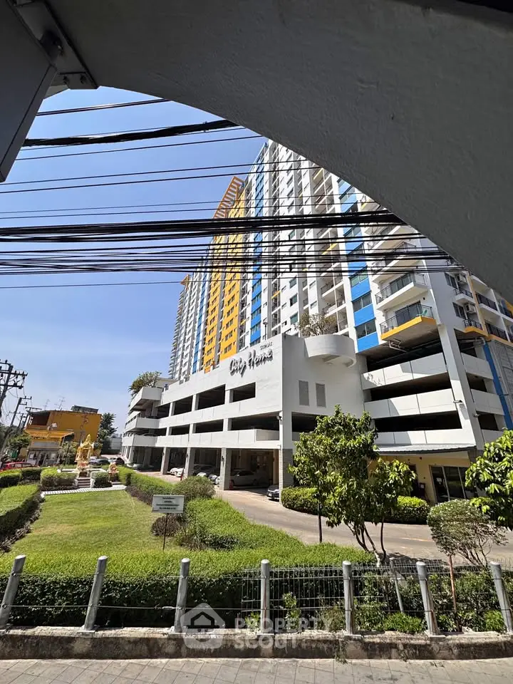 Modern high-rise building with landscaped entrance and clear blue sky