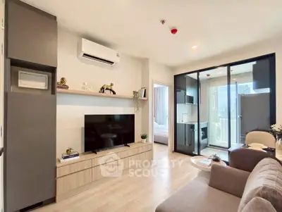 Modern living room with sleek design and large TV, adjacent to a glass-enclosed balcony with city views.