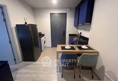Modern kitchen with sleek black appliances and cozy dining area in stylish apartment.