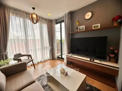 Modern living room with stylish decor, large TV, and balcony view, perfect for relaxation and entertainment.