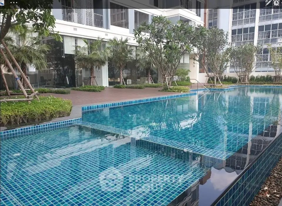 Luxurious condominium pool area with modern design and lush greenery, perfect for relaxation and leisure.