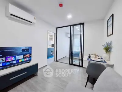 Modern living room with sleek design, featuring a TV, air conditioning, and a view into a stylish bedroom.