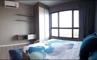 Modern bedroom with large window and stylish decor in a contemporary apartment.