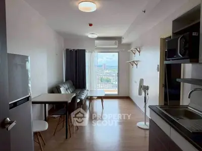 Modern living room with open kitchen and city view, featuring sleek furniture and natural light.