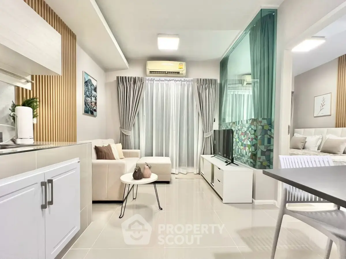 Modern open-plan living room with sleek kitchen and cozy seating area, featuring stylish decor and ample natural light.