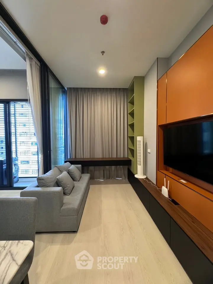 Modern living room with sleek design, featuring a large TV, stylish sofa, and floor-to-ceiling windows with city view.