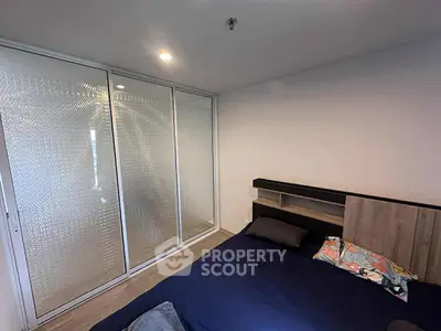 Modern bedroom with sleek sliding glass closet doors and cozy bed setup.