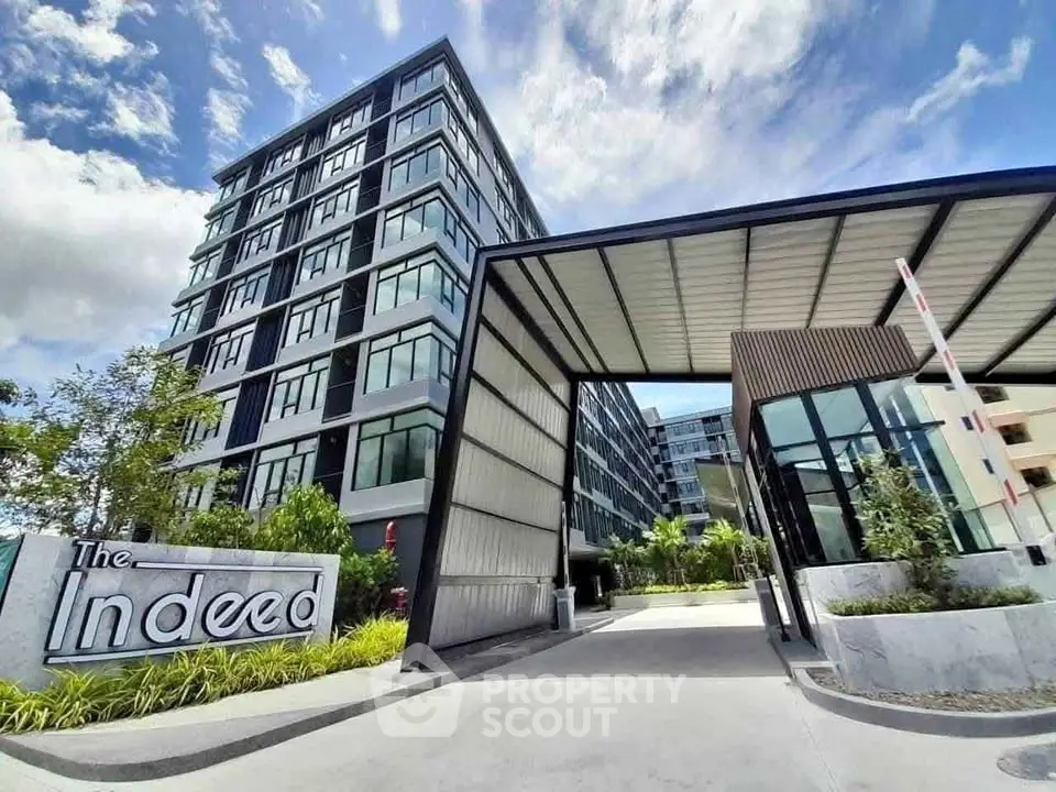 Modern apartment building with stylish entrance and lush landscaping under a vibrant sky.