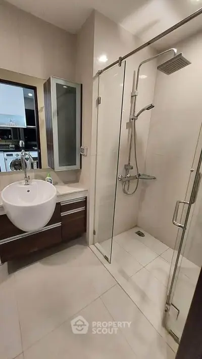 Modern bathroom with glass shower and sleek vanity in contemporary apartment.