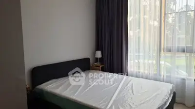 Cozy bedroom with large window and modern furnishings, perfect for relaxation and comfort.