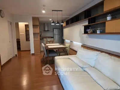 Modern living room with open kitchen, stylish shelving, and cozy seating area.