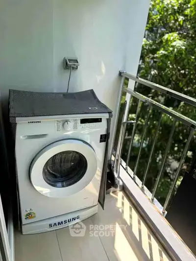 Compact balcony with washing machine and lush green view, perfect for urban living convenience.