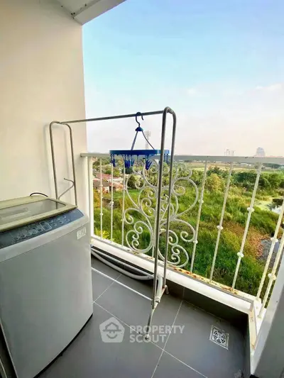 Charming balcony with scenic view and convenient laundry setup in modern apartment.