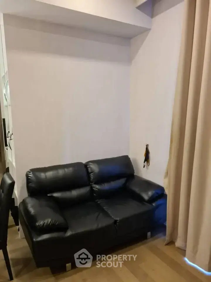 Cozy living room with black leather sofa and wooden flooring, perfect for modern urban living.