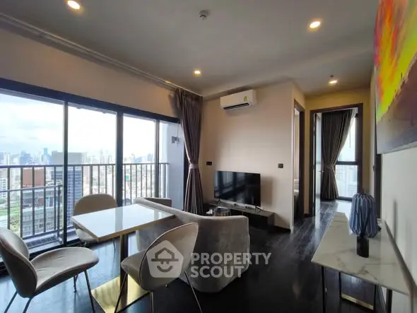 Modern living room with city view, featuring sleek furniture and large windows for natural light.