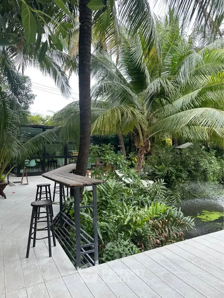 Tropical garden with lush greenery and modern patio seating, perfect for relaxation.
