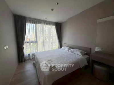 Modern bedroom with large window and city view, featuring a neatly made bed and elegant curtains.