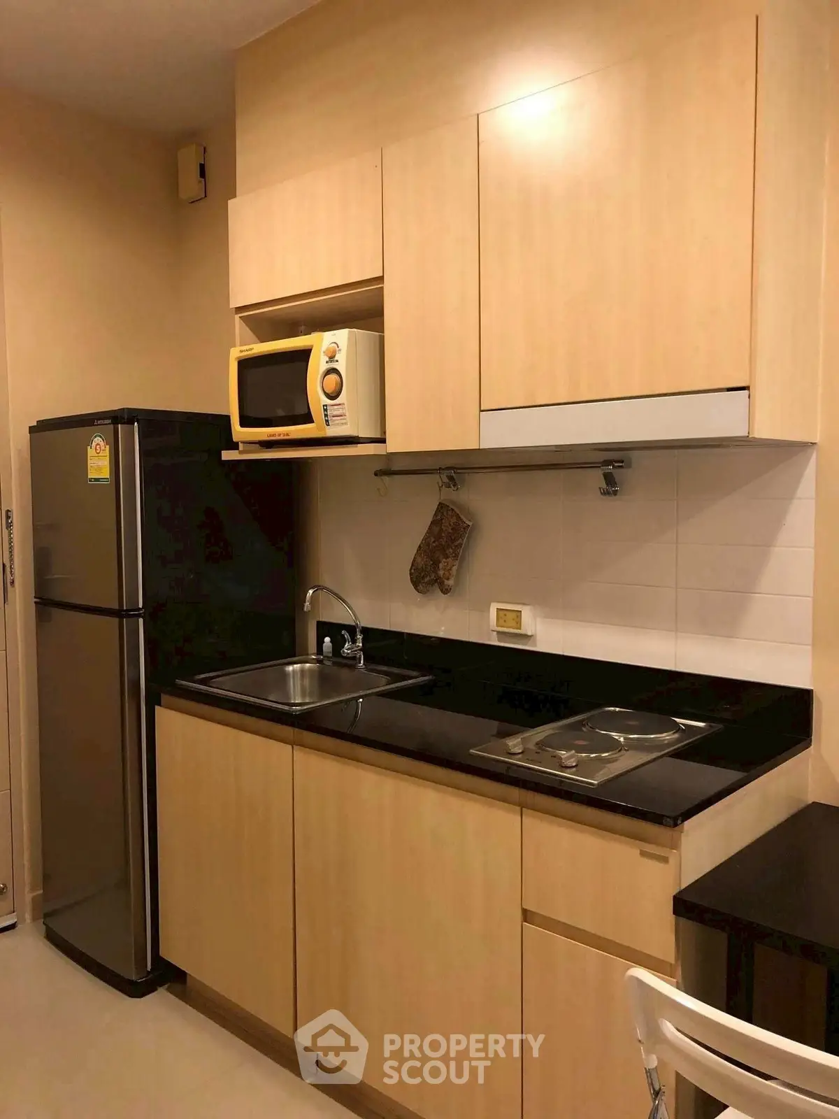 Modern compact kitchen with wooden cabinets and stainless steel appliances