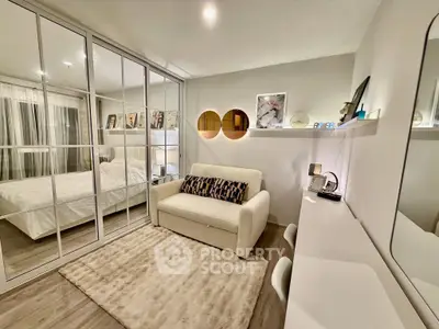 Stylish bedroom with mirrored closet and cozy seating area, perfect for relaxation.