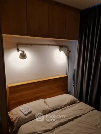 Cozy bedroom with wooden headboard and modern lighting, perfect for relaxation.