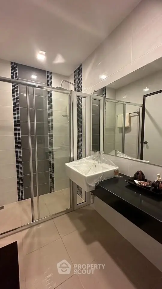 Modern bathroom with sleek glass shower and stylish sink in contemporary design.