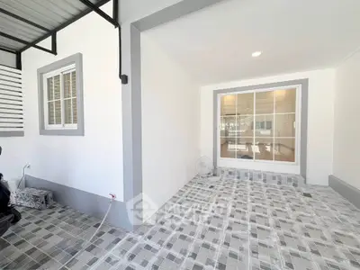 Modern covered patio with tiled flooring and large window, perfect for relaxation and outdoor gatherings.