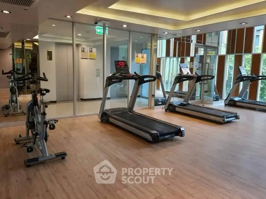 Modern gym with treadmills and exercise bike in a sleek residential building.