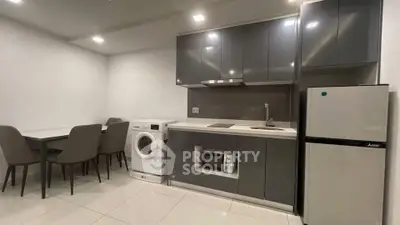 Modern kitchen with sleek cabinetry, dining area, and appliances including washing machine and fridge.