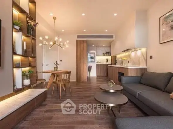 Modern living room with elegant decor and open kitchen layout, featuring stylish lighting and wooden flooring.