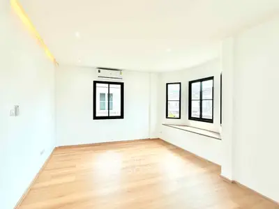 Spacious bright room with large windows and wooden flooring, ideal for modern living.