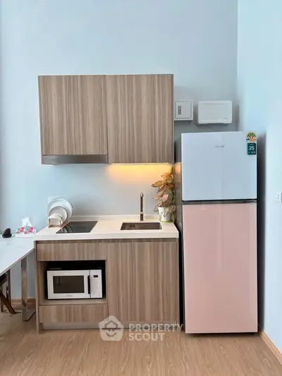 Modern kitchen with sleek cabinetry, built-in microwave, and stylish fridge in a compact layout.