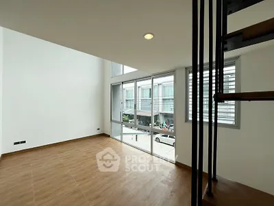 Spacious modern living room with large windows and wooden flooring, featuring a stylish staircase.