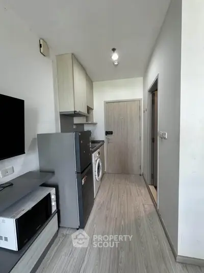 Modern apartment hallway with washing machine and fridge, sleek wooden flooring.