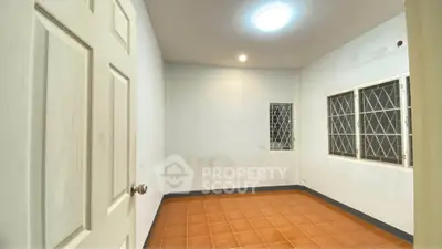 Spacious unfurnished room with tiled floor and barred windows, ideal for customization.