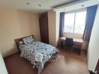 Cozy bedroom with city view, featuring a bed and study desk, perfect for urban living.