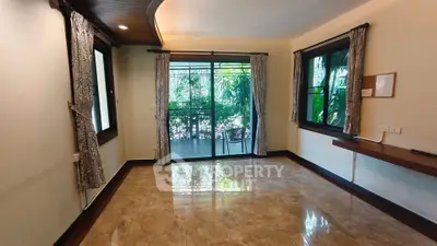 Spacious living room with marble flooring and large windows opening to a lush balcony view.