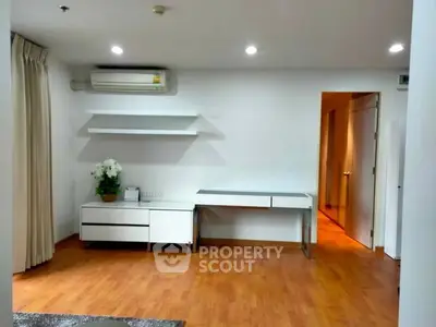 Modern minimalist living space with wooden flooring and sleek white furniture.