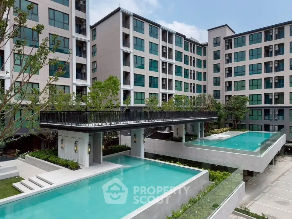 Modern apartment complex with two stunning outdoor pools and lush greenery.