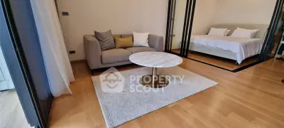 Modern living room with cozy sofa and elegant marble coffee table, adjacent to a stylish bedroom.