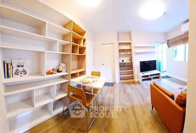 Modern living room with stylish shelving and cozy dining area in open layout apartment.