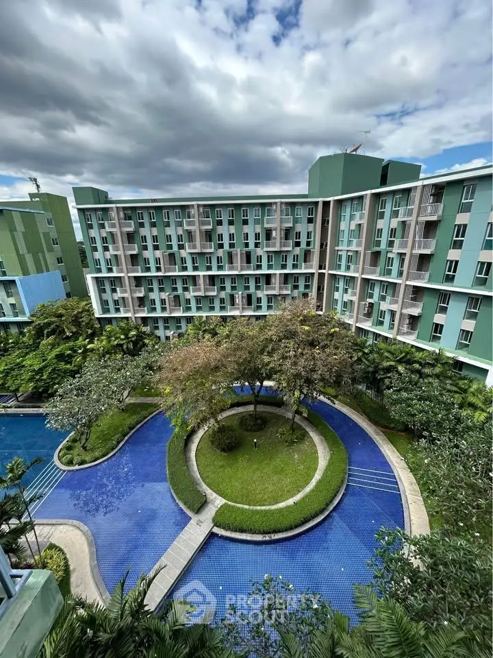 Stunning view of modern apartment complex with lush gardens and serene pool area.