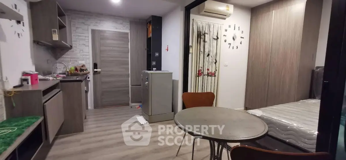 Modern studio apartment with open layout, featuring compact kitchen and cozy living area.