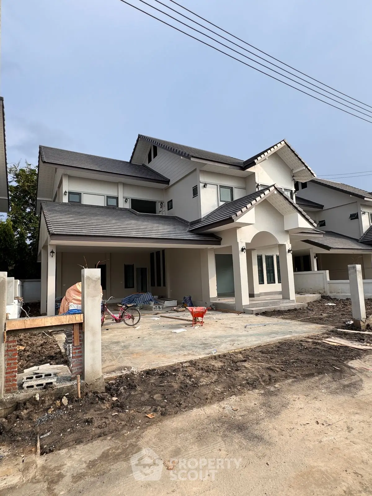 Modern two-story house under construction with spacious driveway and contemporary design.