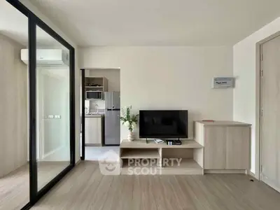 Modern living room with sleek TV setup and sliding glass doors leading to kitchen.