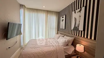 Cozy bedroom with modern decor and striped accent wall, featuring a mounted TV and soft lighting.