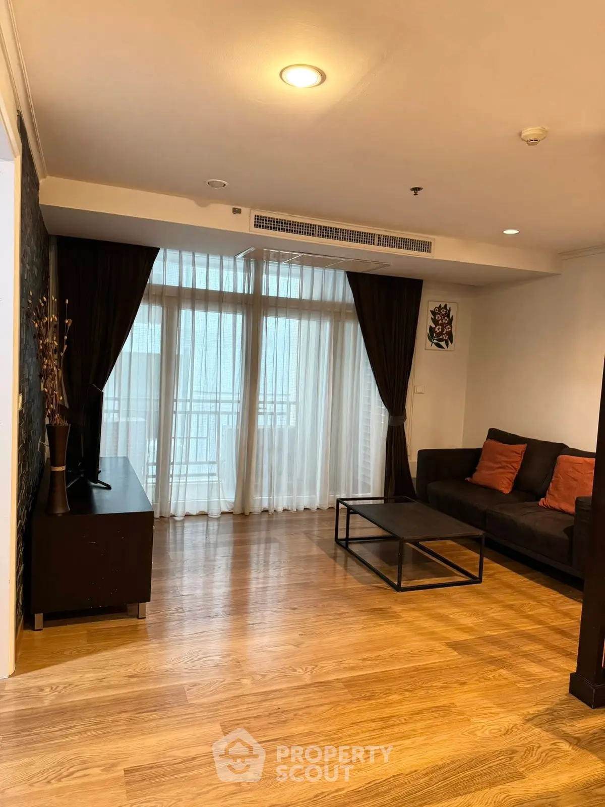 Spacious living room with wooden flooring and large windows for natural light.