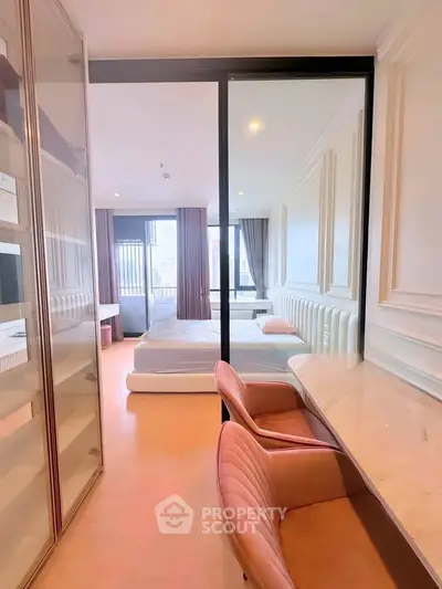 Stylish bedroom with elegant decor and natural light, featuring a cozy workspace and modern furnishings.